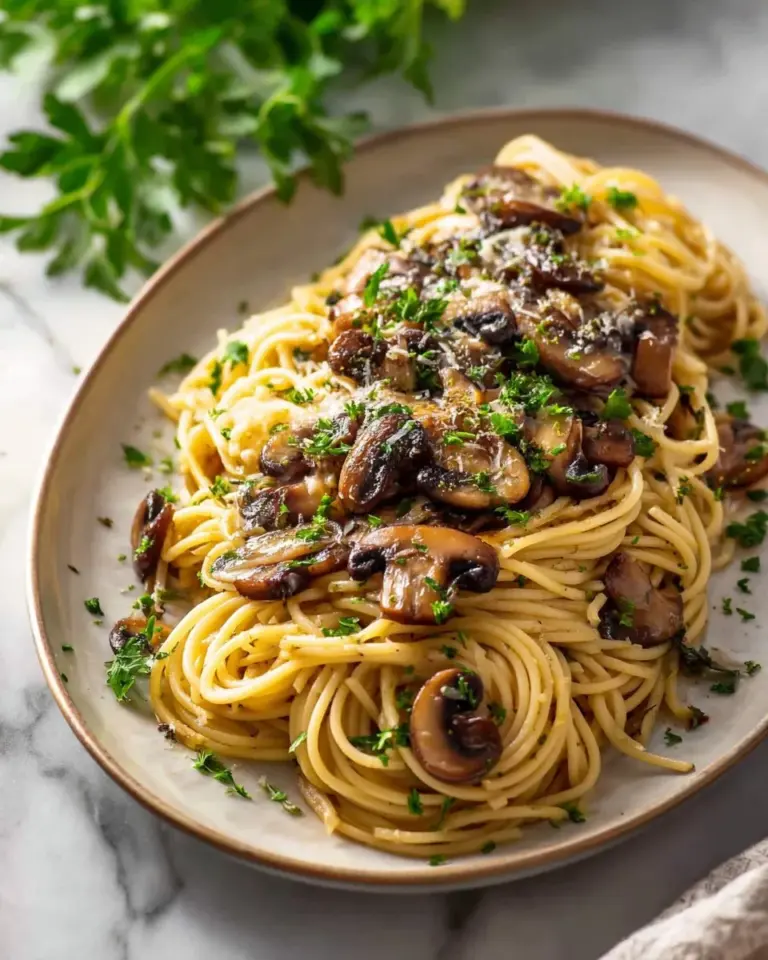 Plate of mushroom pasta drizzled with garlic oil and garnished with herbs