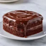 Delicious Chocolate Three Milks Cake topped with chocolate frosting and berries.