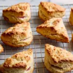 Freshly baked rhubarb scones on a wooden table with a cup of tea