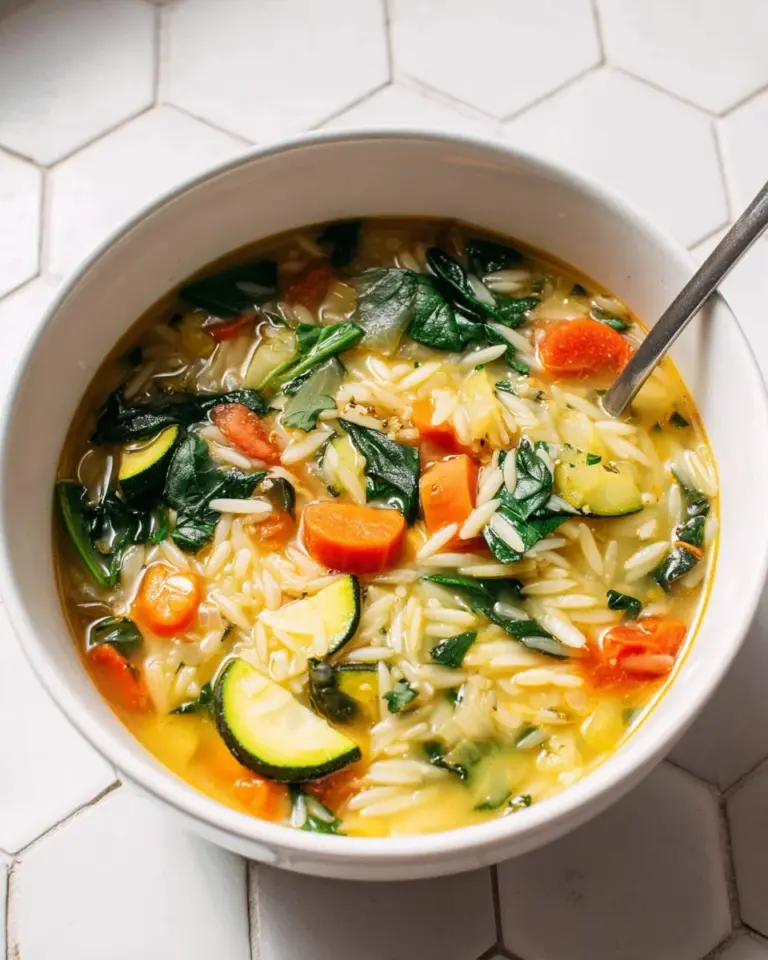 A bowl of hearty Vegetable Orzo Soup filled with fresh vegetables and orzo pasta.